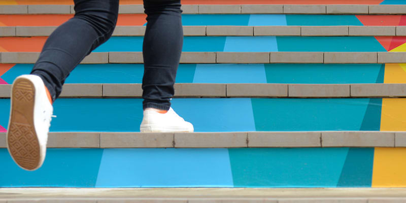 A person walking up colourful stairs
