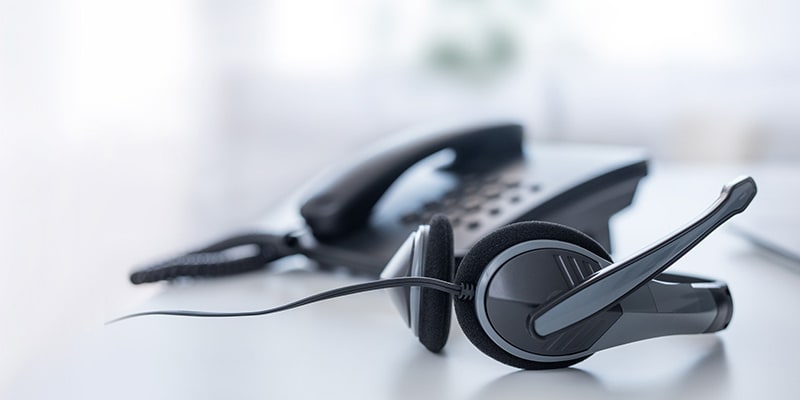 A headset next to a phone on a desk